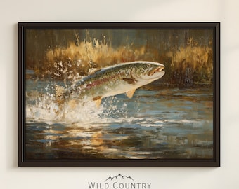 Könnte beinhalten: Gerahmtes Gemälde, das eine Forelle zeigt, die aus dem Wasser springt und einen Spritzer erzeugt. Der Fisch ist detailliert mit Flecken und bunten Farbtönen. Das Kunstwerk ist vor dem Hintergrund eines Flusses und hohem Gras angeordnet. Der Rahmen ist dunkelbraun, und das Logo Wild Country Collective befindet sich unten.