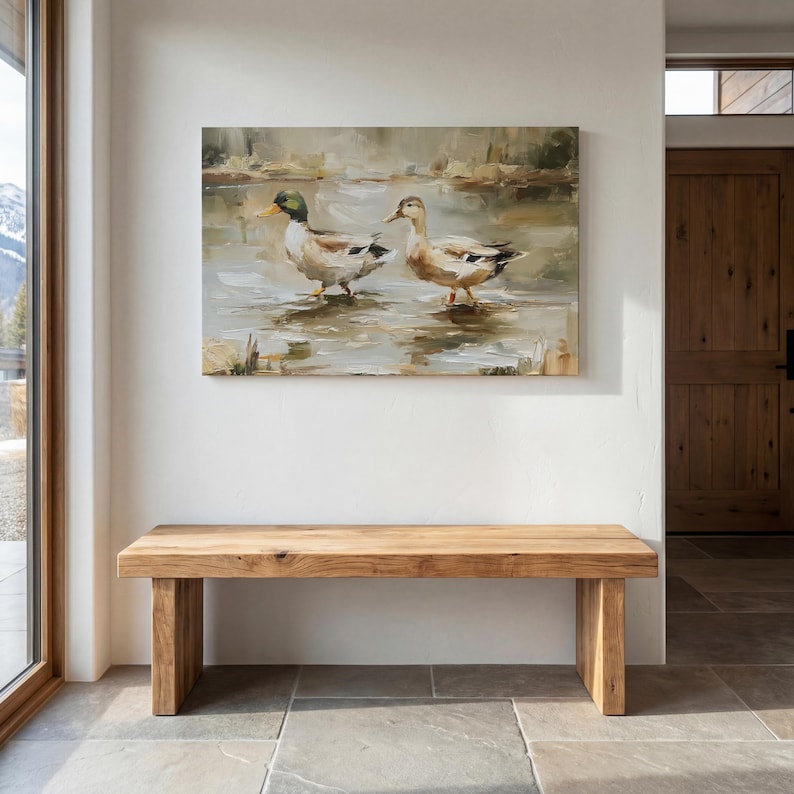 a wooden bench situated in a room with a large painting of ducks hanging on the wall above it.