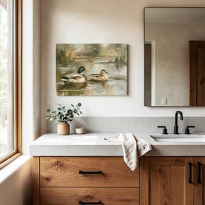 a bathroom with a large mirror, a wooden vanity, and a painting of ducks on the wall.