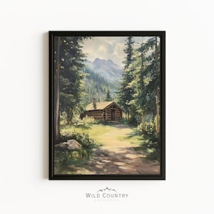 May include: A framed wall art print depicting a rustic log cabin nestled in a dense forest of tall pine trees with a mountain range in the background. The scene features a dirt path leading towards the cabin under a soft, daylight sky.