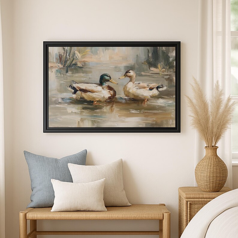 a painting of two ducks swimming in a pond, hanging on a wall above a wooden bench with pillows.