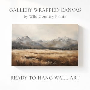 May include: Gallery wrapped canvas wall art featuring a landscape painting of a mountain range with snow-capped peaks. The artwork depicts a field of tall grass in shades of brown and tan. The text reads "Gallery Wrapped Canvas" and "Ready to Hang Wall Art."