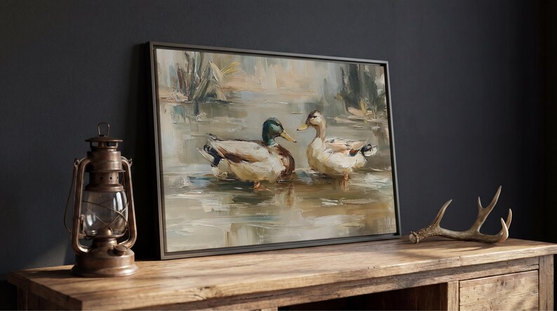 a painting of two ducks in a pond, displayed on a wooden table.