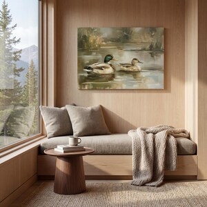 a cozy and inviting living space with a large window overlooking a serene lake, where two ducks are swimming. The room is furnished with a comfortable couch, a small wooden table, and a cozy blanket, creating a warm and relaxing atmosphere.