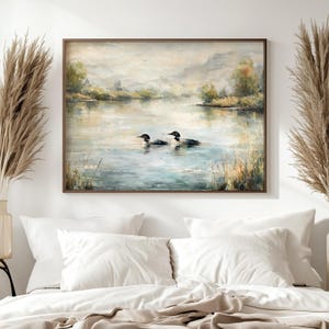 a large painting of two ducks swimming in a lake, hanging on a wall above a bed with white pillows.
