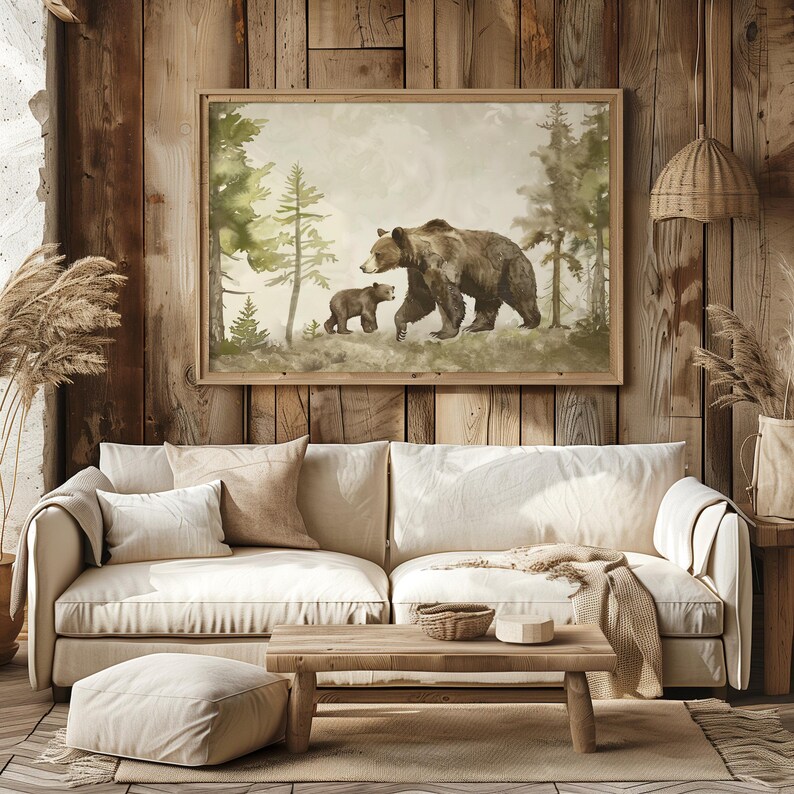May include: A watercolor painting of a brown bear and her cub walking through a forest. The painting is framed in a light wood frame and is hanging on a wooden wall.
