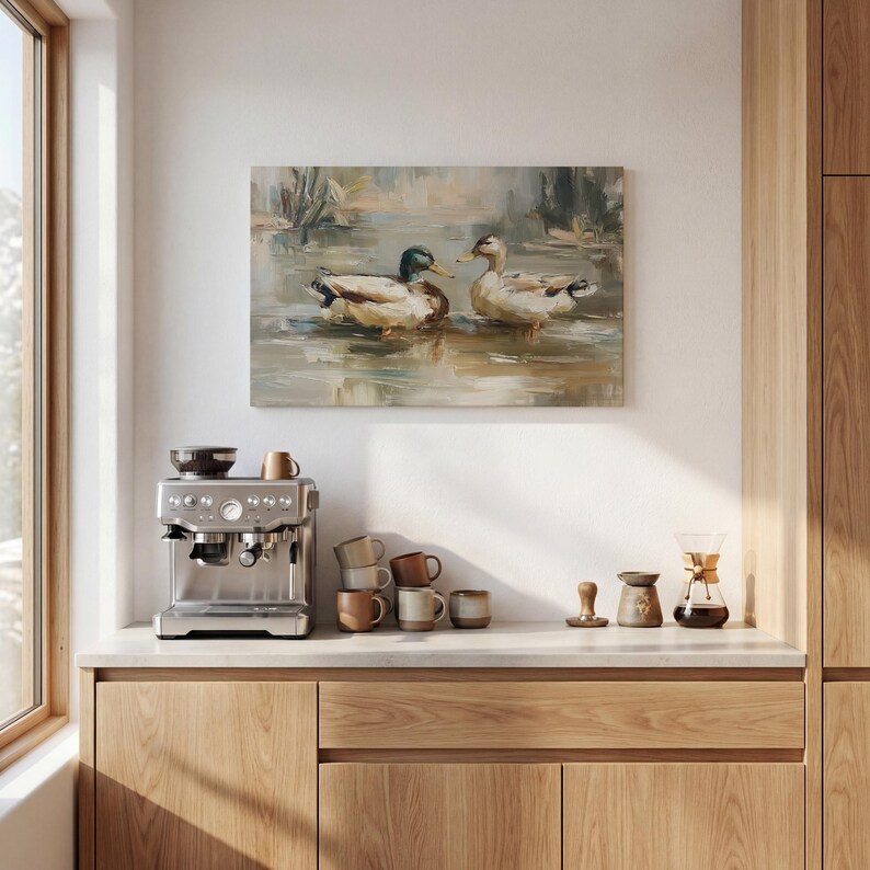 a kitchen counter with a coffee machine, coffee cups, and a painting of ducks swimming in a pond.