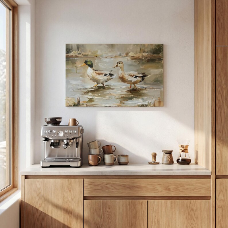 a kitchen counter with a coffee machine, coffee cups, and a painting of ducks in a pond.