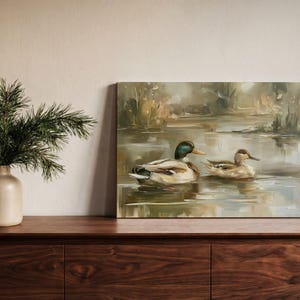 a wooden dresser with a painting of two ducks swimming in a pond, and a vase of pine branches on the left side of the dresser.