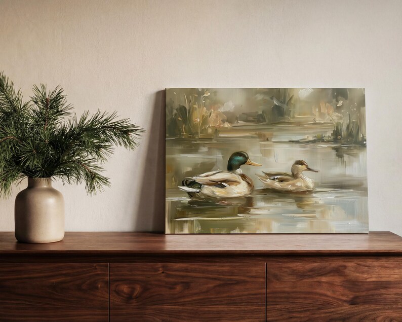 a wooden dresser with a painting of two ducks swimming in a pond, and a vase of pine branches on the left side of the dresser.