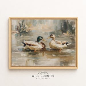 The image is a framed painting depicting two ducks swimming in a body of water, surrounded by a natural landscape.