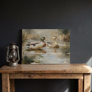 a painting of ducks swimming in a pond, displayed on a wooden table.