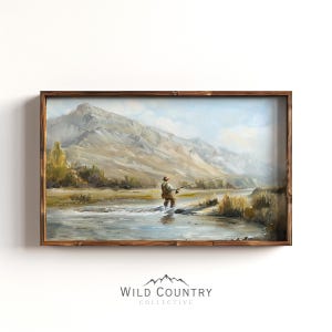 May include: A framed landscape painting shows a person fly fishing in a river, with mountains in the background. The artwork has a rustic wooden frame and features a serene outdoor scene with muted colours.