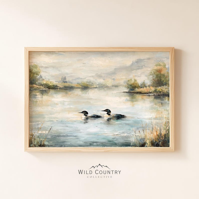 The image is a framed painting depicting two loon birds swimming in a lake, surrounded by a serene landscape with trees and mountains in the background.
