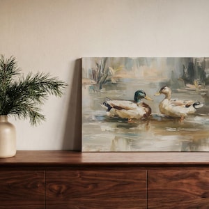 a painting of two ducks swimming in a pond, displayed on a wooden shelf next to a vase with greenery.
