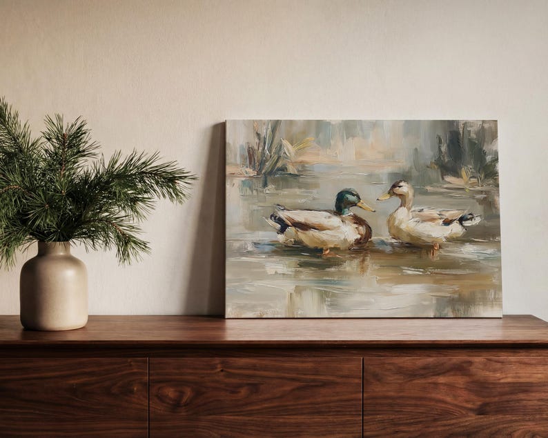 a painting of two ducks swimming in a pond, displayed on a wooden shelf next to a vase with greenery.