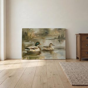 a painting of two ducks swimming in a pond, displayed on a wall in a room with a wooden floor.
