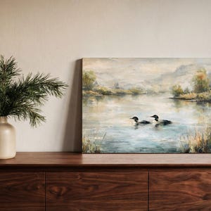 a painting of two ducks swimming in a lake, with a vase of pine branches and a wooden dresser in the foreground.