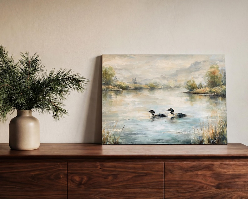 a painting of two ducks swimming in a lake, with a vase of pine branches and a wooden dresser in the foreground.