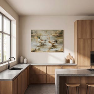 a modern kitchen with wooden cabinets, a large window, and a painting of ducks on the wall.