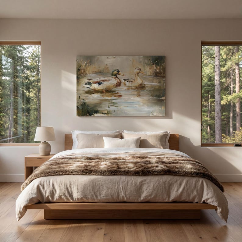 a serene bedroom scene with a large bed, a painting of ducks in a pond, and two windows overlooking a forest.