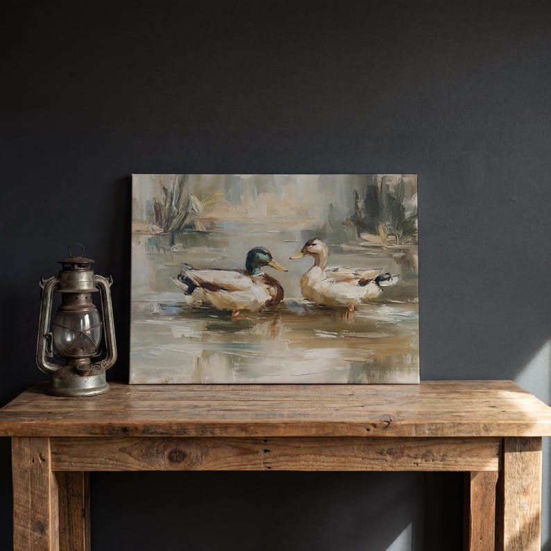 a painting of two ducks swimming in a body of water, displayed on a wooden table.