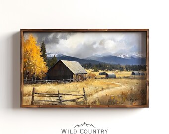 May include: A framed oil painting of a rustic wooden barn with a metal roof, surrounded by a wooden fence and a field of golden grass. The barn is set against a backdrop of snow-capped mountains and a cloudy sky. The painting is signed "Wild Country Collective".