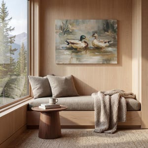 a cozy and inviting living space with a large window overlooking a serene lake, where two ducks are swimming. The room is adorned with a painting of ducks on the wall, a wooden bench, a small side table, and a beige blanket draped over the bench.