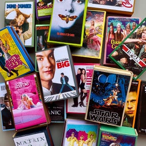 May include: A collection of vintage movie VHS tapes with various titles including "Dumb and Dumber", "Austin Powers", "The Silence of the Lambs", "Top Gun", "Star Wars", and "Big".
