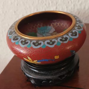 Antique bowl of authentic Chinese floral cloisonne enamel. On a wooden stand. Cloisonne ornament, enameled figure vintage