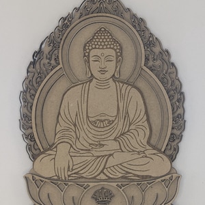 May include: A wooden Buddha pendant in a seated meditation pose. The pendant is a light brown colour and features intricate details, including a halo, lotus flower base, and decorative flame-like border. A small hole is at the top for hanging.