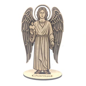 Puede incluir: Figura de ángel de madera con alas detalladas, un halo y un corazón. El ángel sostiene un corazón y está de pie sobre una base redonda con el nombre "Chamuel" grabado. La figura es de madera marrón claro.