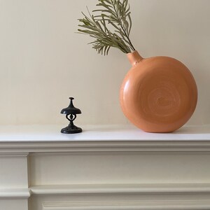 FACE of Sienna ceramic vase with a beautiful green leaf on a fireplace.