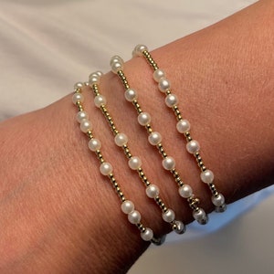 May include: A bracelet made of multiple strands of small white pearls and gold beads.