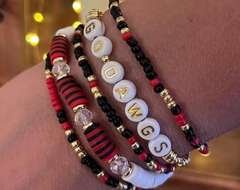 May include: A set of six bracelets with black, red, and gold beads. The bracelets spell out "GO DAWGS" in white beads with gold lettering.