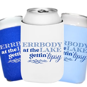 Könnte beinhalten: Drei Getränkedosenkühler in Blau und Weiß. Die Kühler tragen den Text "ERRBODY at the LAKE gettin' tipsy" in Blau. Das Design beinhaltet Wellengrafiken. Die Dosen sind silberfarben.