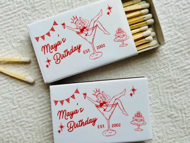Custom martini-themed birthday matchboxes are shown with the matchbox open. The matches feature the design of a woman in a martini glass beside a birthday message for martini-themed birthday parties and party favors.