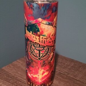 May include: A stainless steel tumbler with a colorful design featuring the band Judas Priest and the text "Incredible Shr" on the bottom.