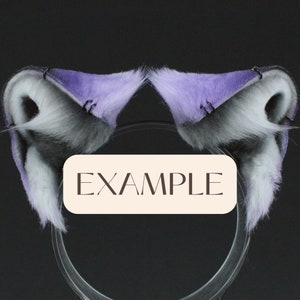 May include: A pair of purple and gray faux fur cat ears with black metal hoops. The ears are attached to a clear plastic headband. The headband is labeled "EXAMPLE".