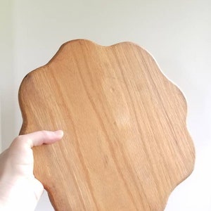K&ouml;nnte beinhalten: Ein Serviertablett aus Holz mit einer einzigartigen, unregelm&auml;&szlig;igen Form. Das Tablett ist aus hellbraunem Holz mit nat&uuml;rlicher Maserung.