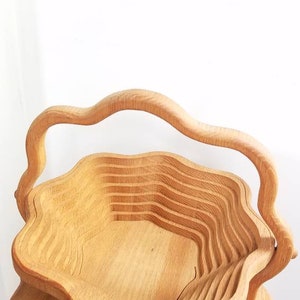 K&ouml;nnte beinhalten: Eine ausziehbare, blumenf&ouml;rmige Servierschale aus Holz mit einem Griff. Die Schale ist aus hellbraunem Holz gefertigt und hat eine nat&uuml;rliche Oberfl&auml;che.