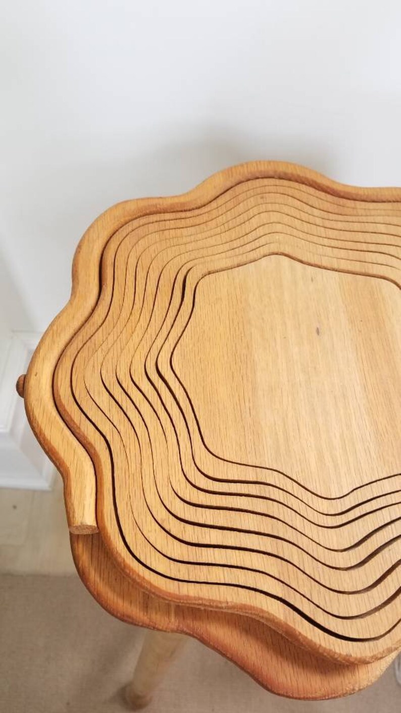 K&ouml;nnte beinhalten: Ein Holztisch mit einem einzigartigen, wellenf&ouml;rmigen Design. Der Tisch besteht aus mehreren Holzschichten, die einen geschichteten Effekt erzeugen. Der Tisch ist hellbraun und hat eine nat&uuml;rliche Holzoptik.