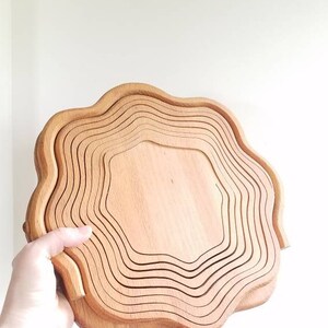 K&ouml;nnte beinhalten: Eine Holzobstschale mit gewelltem Rand. Die Schale besteht aus mehreren &uuml;bereinander gestapelten Holzschichten. Die Schale ist hellbraun.