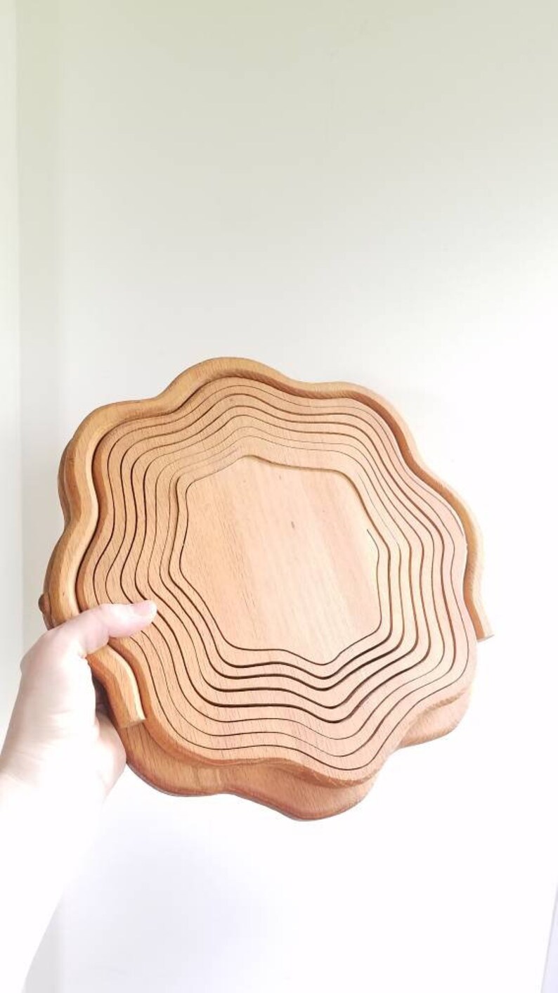 K&ouml;nnte beinhalten: Eine Holzobstschale mit gewelltem Rand. Die Schale besteht aus mehreren &uuml;bereinander gestapelten Holzschichten. Die Schale ist hellbraun.