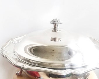 以下が含まれることがあります： 蓋と3本の装飾的な足が付いた銀製のサービングディッシュ。ディッシュは丸く、波打った縁があります。