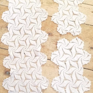 May include: Three white crocheted doilies with a swirling pattern. The doilies are on a wooden surface.