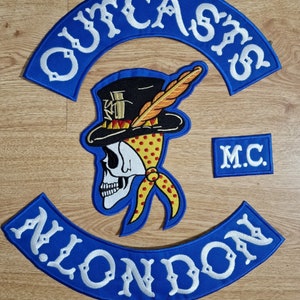 May include: Embroidered patches featuring a skull wearing a top hat and bandana, with the text "OUTCASTS" and "LONDON" in white on blue arcs. A smaller patch reads "M.C."