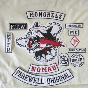 Puede incluir: Un conjunto de parches bordados que representan una cabeza de perro gruñendo con una cadena, las palabras "Mongrels", "Nomad", "Farewell Original", "F.T.W", "MFFM", "Enforcer MC", "1% Road Captain" y "Vagabond MC Biker Riding Free 1979".