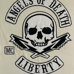 May include: Black and white embroidered patch with a skull and crossbones design. The patch reads "Angels of Death" in a curved arch above the skull and "Liberty" in a curved arch below the skull. The patch also includes the letters "MC" in a square.