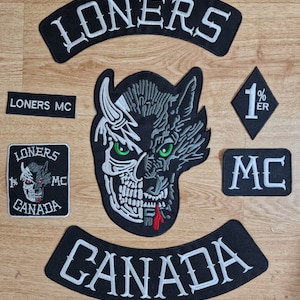 Peut inclure: Un ensemble de patchs brodés noirs et blancs avec les mots "Loners MC" et "Canada" en lettres blanches. Les patchs présentent également un crâne de loup et un diamant 1%er.